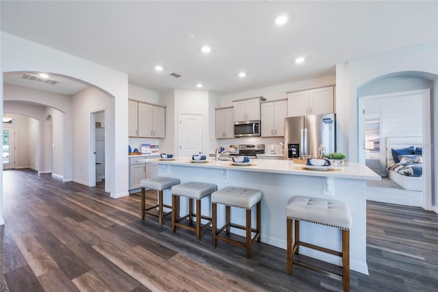 1974 Walnut Creek Dr, Kissimmee, FL 34744 - kitchen featuring appliances with stainless steel finishes, arched walkways, a breakfast bar area, dark wood-style flooring, and recessed lighting