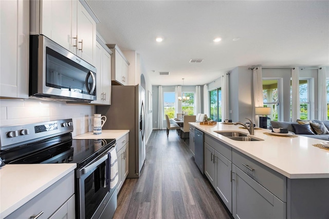 1974 Walnut Creek Dr, Kissimmee, FL 34744 - kitchen with stainless steel appliances, a sink, gray cabinetry, dark wood-type flooring, and light countertops
