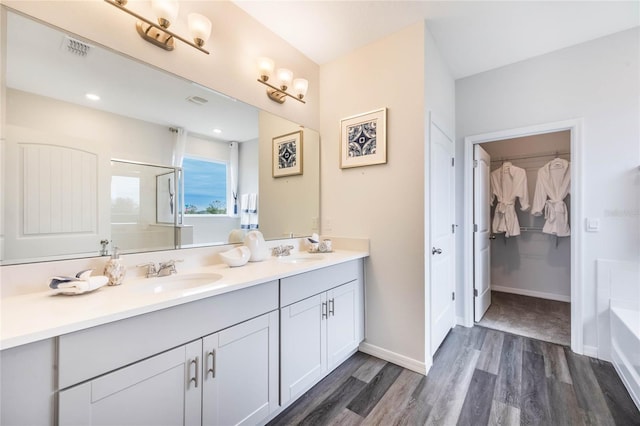 1974 Walnut Creek Dr, Kissimmee, FL 34744 - bathroom featuring wood finished floors, double vanity, a tub to relax in, a walk in closet, and a shower