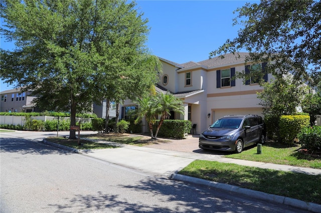 view of front of house featuring stucco siding, an attached garage, and fence