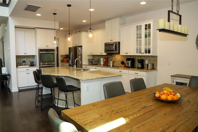 9005 Reflection Pointe Dr, Windermere, FL 34786 - kitchen with appliances with stainless steel finishes, a sink, tasteful backsplash, a kitchen island with sink, and a kitchen breakfast bar