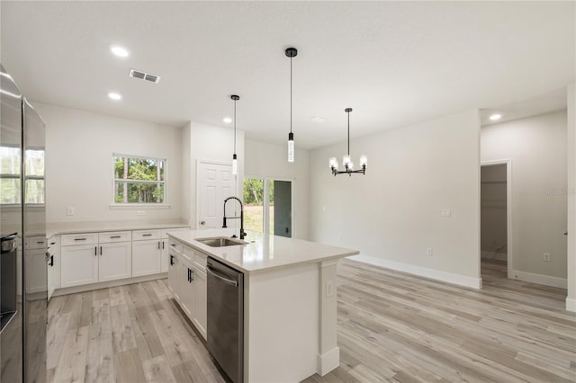 kitchen featuring stainless steel dishwasher, a sink, light wood-style flooring, a chandelier, and recessed lighting