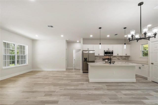 kitchen with stainless steel appliances, a sink, a chandelier, light countertops, and recessed lighting