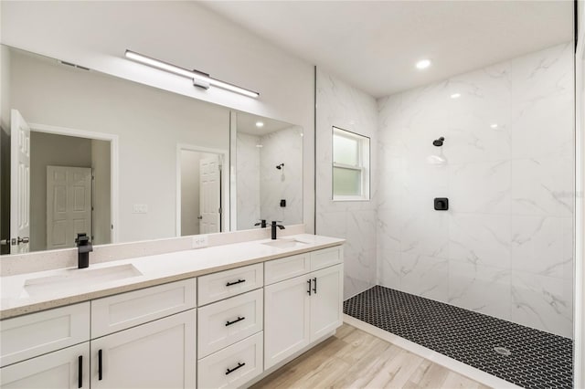full bath featuring a marble finish shower, double vanity, and wood finished floors