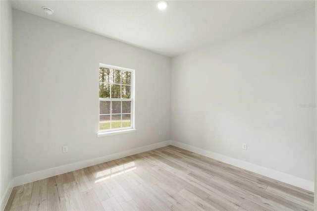 unfurnished room with baseboards, light wood-type flooring, recessed lighting, and a smoke detector