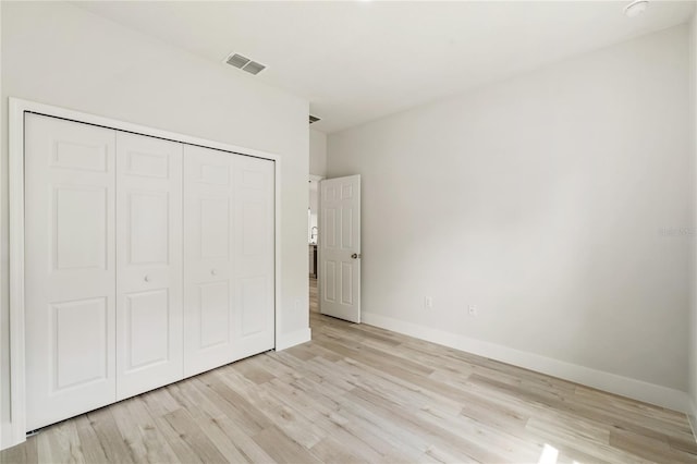 unfurnished bedroom with light wood-type flooring, baseboards, and a closet