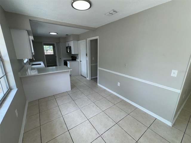 6624 Kristin Ct, Orlando, FL 32818 - kitchen featuring white cabinetry, light tile patterned floors, light countertops, black appliances, and baseboards