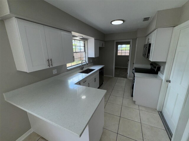6624 Kristin Ct, Orlando, FL 32818 - kitchen featuring black appliances, a sink, a peninsula, white cabinetry, and light countertops