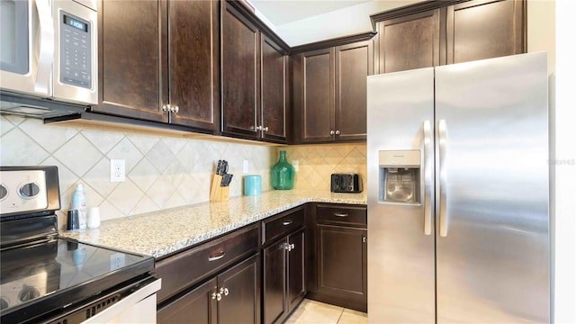 2030 Majorca Dr, Kissimmee, FL 34747 - kitchen with stainless steel appliances, light stone counters, dark brown cabinetry, backsplash, and light tile patterned floors