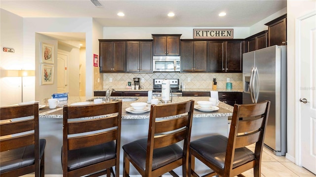 2030 Majorca Dr, Kissimmee, FL 34747 - kitchen featuring stainless steel appliances, dark brown cabinetry, backsplash, a sink, and recessed lighting
