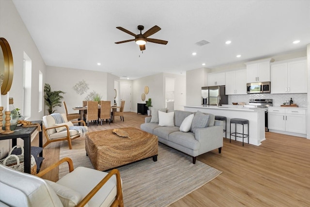 living area featuring ceiling fan, light wood-style floors, and recessed lighting