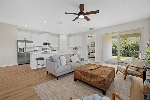 living area featuring ceiling fan, light wood finished floors, baseboards, and recessed lighting
