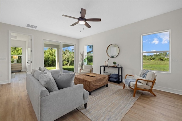 living area with light wood-style flooring, ceiling fan, and baseboards