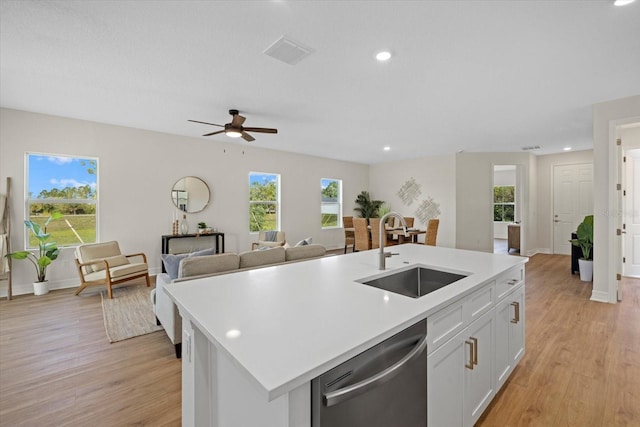 kitchen with a sink, stainless steel dishwasher, light wood-style flooring, light countertops, and white cabinetry