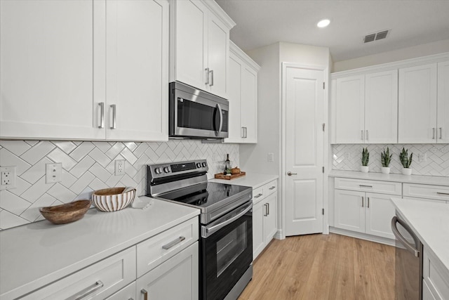 kitchen with stainless steel appliances, light countertops, white cabinetry, backsplash, and light wood-type flooring