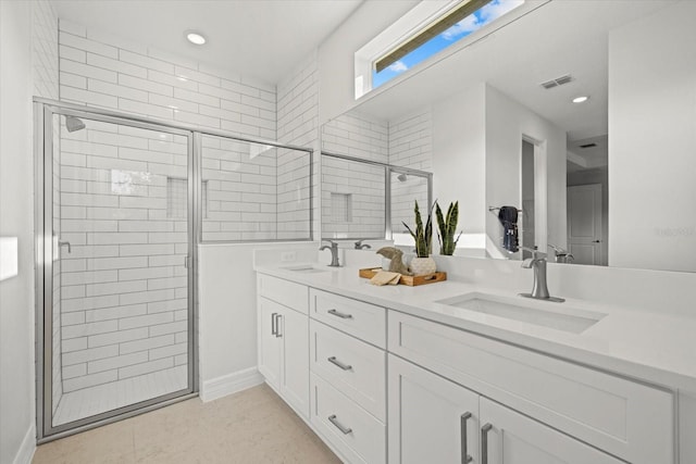 bathroom featuring a shower stall, double vanity, recessed lighting, and baseboards