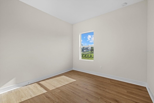 unfurnished room featuring wood finished floors, baseboards, and a smoke detector