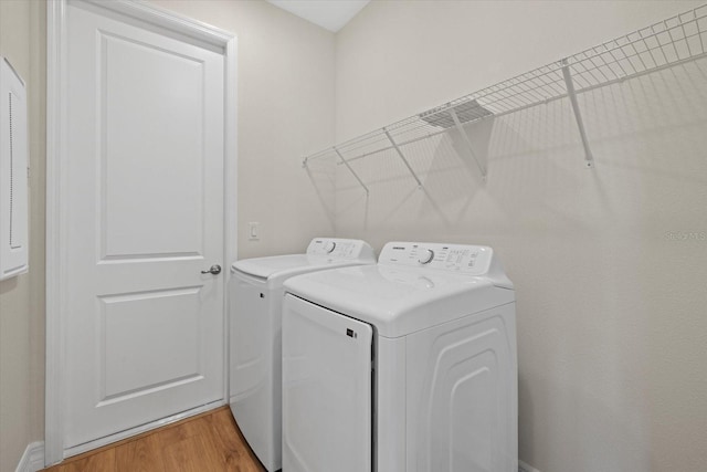 laundry area with washing machine and dryer and light wood-style flooring
