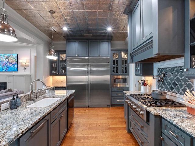 9916 Lone Tree Ln, Orlando, FL 32836 - kitchen featuring built in appliances, a sink, light wood finished floors, backsplash, and light stone counters