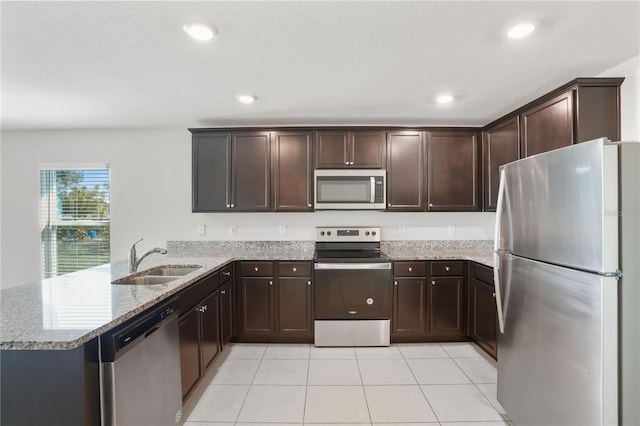 1119 Union Ave, Mascotte, FL 34753 - kitchen with stainless steel appliances, a sink, light stone countertops, a peninsula, and dark brown cabinetry
