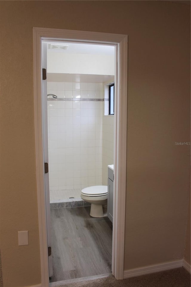 full bath with wood finished floors, toilet, a stall shower, vanity, and baseboards