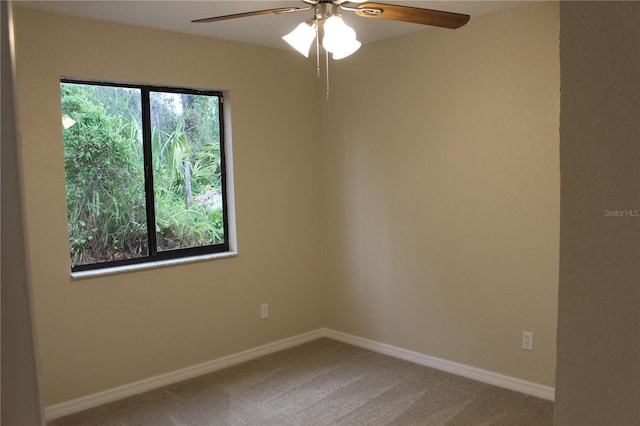 carpeted empty room featuring ceiling fan and baseboards
