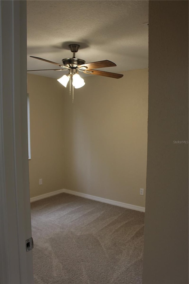 unfurnished room with carpet, ceiling fan, baseboards, and a textured ceiling