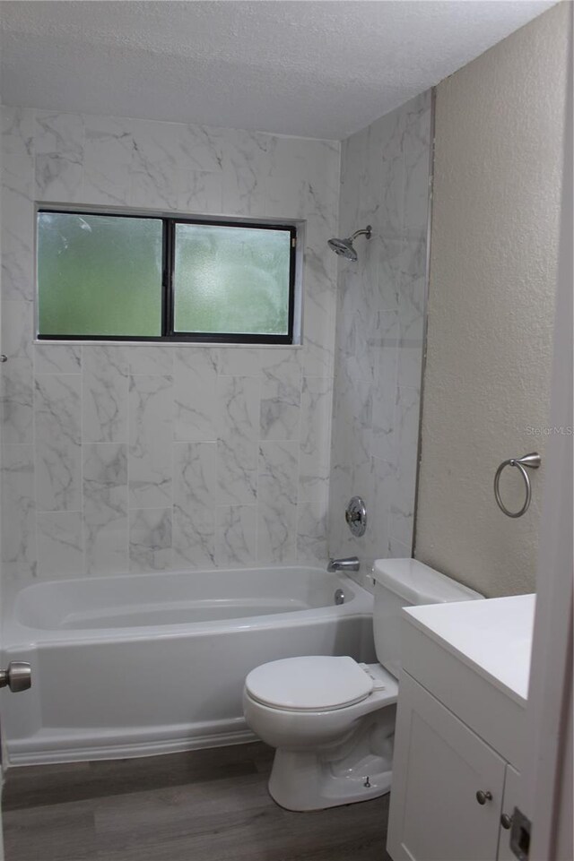 bathroom with wood finished floors, a textured wall, shower / bathtub combination, toilet, and a textured ceiling