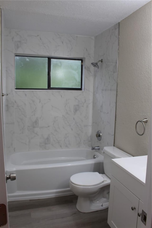 bathroom with wood finished floors, a textured wall, toilet, shower / washtub combination, and a textured ceiling