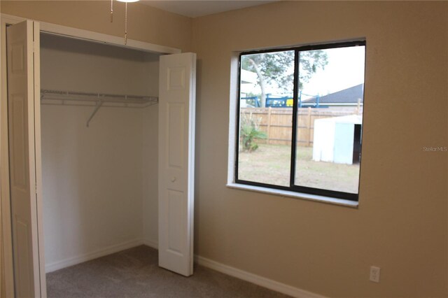 unfurnished bedroom featuring carpet floors, a closet, and baseboards