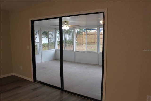 doorway featuring a ceiling fan, wood finished floors, and baseboards