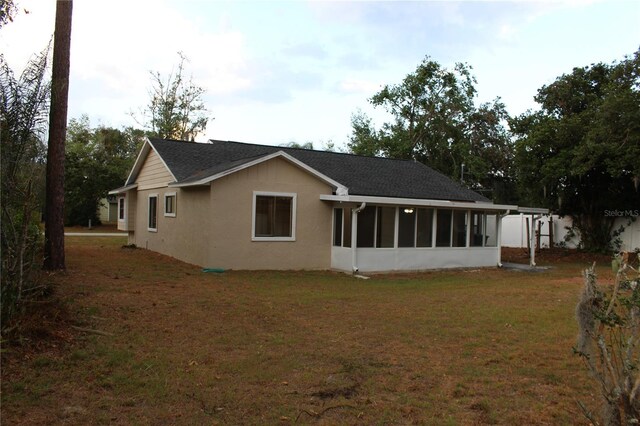 back of house featuring a sunroom and a lawn