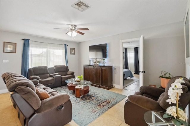 living area with light tile patterned floors, healthy amount of natural light, a ceiling fan, and baseboards