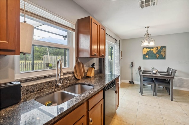 kitchen with a sink, stainless steel dishwasher, brown cabinetry, hanging light fixtures, and baseboards