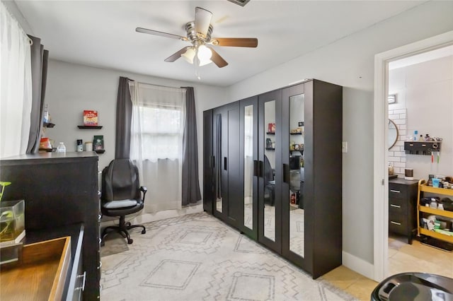 home office featuring ceiling fan, baseboards, and light tile patterned flooring