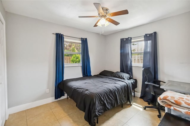 bedroom with light tile patterned flooring, ceiling fan, and baseboards