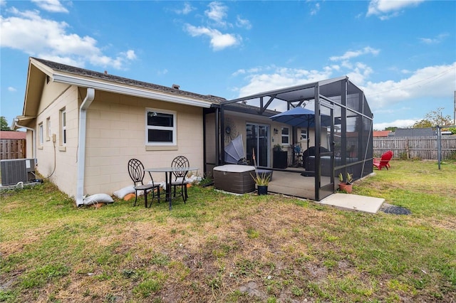 rear view of house featuring central air condition unit, a lanai, concrete block siding, and a patio