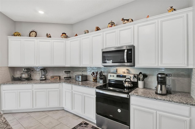 208 Summerlin Ln, Haines City, FL 33844 - kitchen with stainless steel appliances, decorative backsplash, light tile patterned floors, and white cabinets