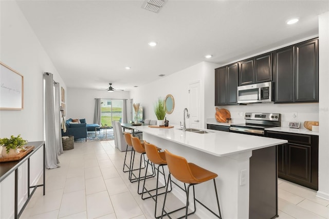 6834 Wilson Hammock Ave, Groveland, FL 34736 - kitchen with stainless steel appliances, a sink, open floor plan, a breakfast bar area, and a ceiling fan