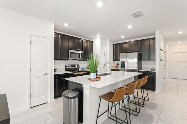 6834 Wilson Hammock Ave, Groveland, FL 34736 - kitchen featuring appliances with stainless steel finishes, a sink, light tile patterned floors, a breakfast bar area, and light countertops