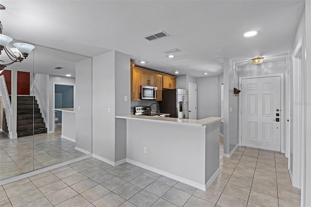 2498 Saint Augustine Blvd, Haines City, FL 33844 - kitchen with stainless steel appliances, light tile patterned flooring, light countertops, brown cabinetry, and recessed lighting