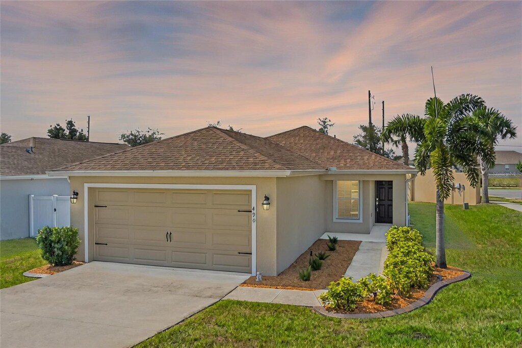 490 Pentas Ln, Haines City, FL 33844 - ranch-style house featuring a garage, stucco siding, driveway, a lawn, and roof with shingles