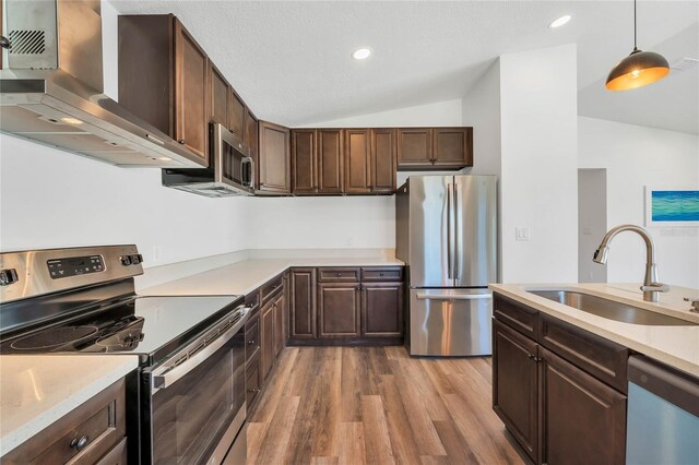 1040 20th St, Orlando, FL 32805 - kitchen with stainless steel appliances, a sink, vaulted ceiling, wall chimney exhaust hood, and wood finished floors