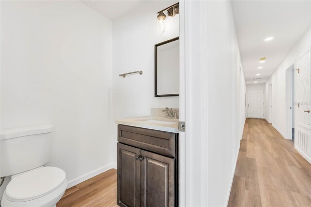 1040 20th St, Orlando, FL 32805 - bathroom with wood finished floors, toilet, vanity, baseboards, and recessed lighting