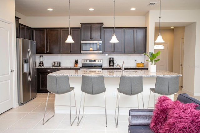 8944 Sydney Ave, Kissimmee, FL 34747 - kitchen with appliances with stainless steel finishes, backsplash, a sink, dark brown cabinets, and a breakfast bar