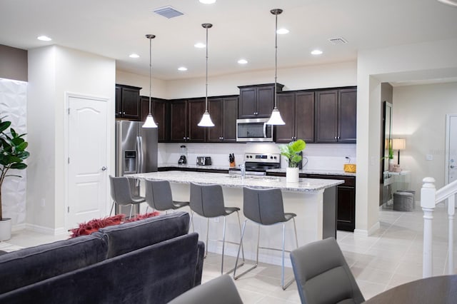 8944 Sydney Ave, Kissimmee, FL 34747 - kitchen featuring stainless steel appliances, backsplash, open floor plan, dark brown cabinets, and light stone countertops