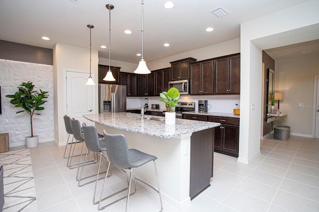 8944 Sydney Ave, Kissimmee, FL 34747 - kitchen with appliances with stainless steel finishes, dark brown cabinetry, light stone counters, recessed lighting, and light tile patterned floors