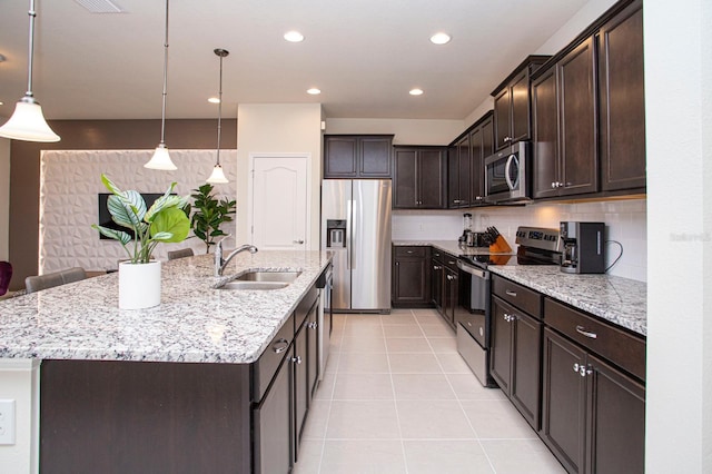 8944 Sydney Ave, Kissimmee, FL 34747 - kitchen featuring appliances with stainless steel finishes, a sink, dark brown cabinetry, an island with sink, and light tile patterned flooring