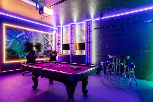 playroom featuring a textured ceiling, billiards table, and concrete block wall