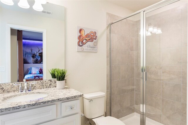 ensuite bathroom featuring a shower stall, vanity, and toilet